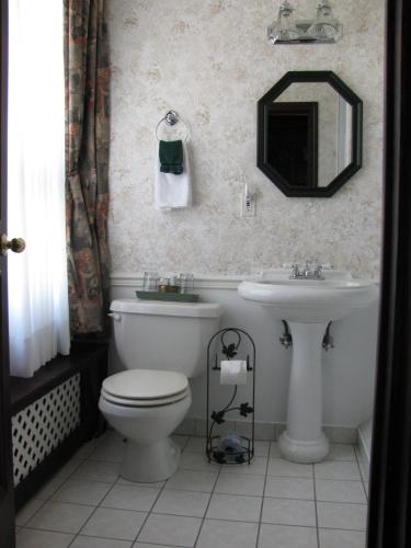 a bathroom with a sink and a toilet and a mirror at The King George Inn in Cobourg