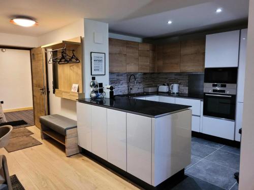 une cuisine avec des armoires blanches et un comptoir noir dans l'établissement Résidence Diamant Des Cimes - Appartement haut de gamme 9 personnes MAE-3234, à Montvalezan