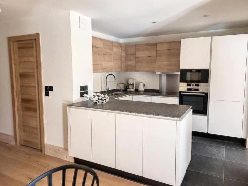 une cuisine avec des armoires blanches et un comptoir dans l'établissement Résidence Diamant Des Cimes - Appartement Haute Gamme avec vue sur la vallée MAE-3264, à Montvalezan