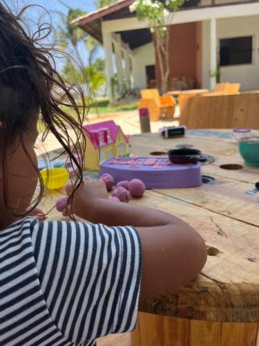 a little girl sitting on a wooden table at Pousada Vila Flow in Cumbuco