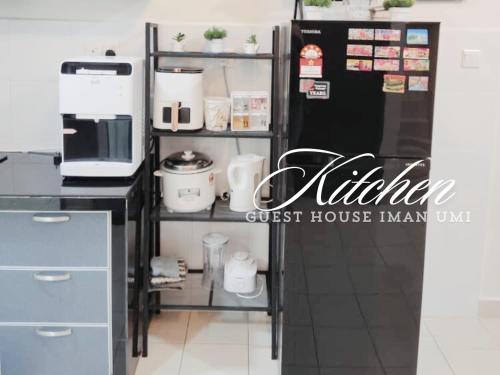 a kitchen with a black refrigerator next to a counter at Guest House Iman Umi Bagan Serai in Bagan Serai