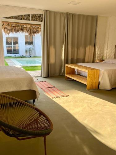 a bedroom with two beds and a chair and a window at Pousada Vila Flow in Cumbuco