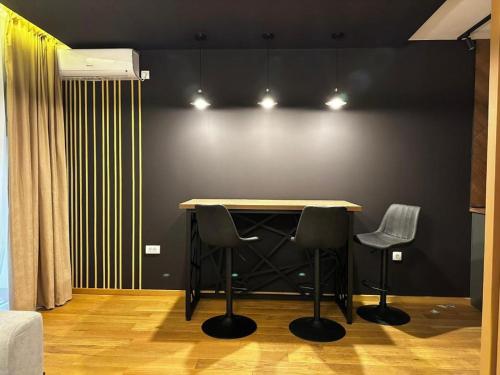 a room with a table and two chairs against a wall at LUXURY APARTMAN ELENI ROOMS oaza mira i tišine u centru Vrnjačke banje in Vrnjačka Banja