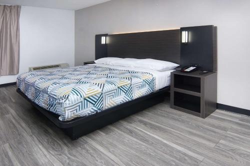 a bedroom with a large bed and a night stand at Motel 6-Fort Worth, TX - Downtown East in Fort Worth