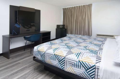 a hotel room with a bed and a desk and a television at Motel 6-Fort Worth, TX - Downtown East in Fort Worth