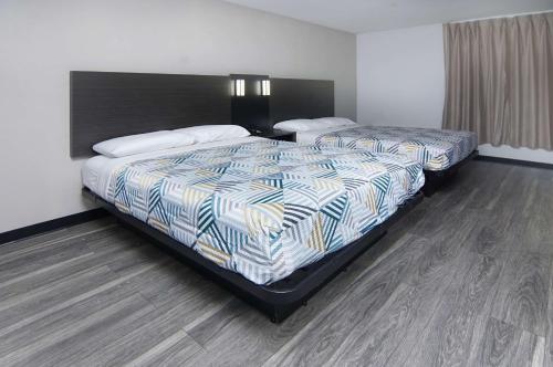 two beds in a room with wood floors at Motel 6-Fort Worth, TX - Downtown East in Fort Worth