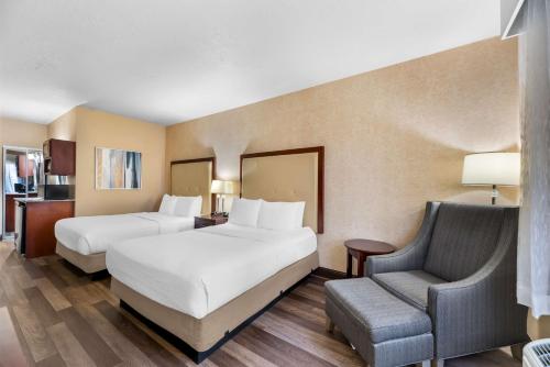 a hotel room with two beds and a chair at Best Western Plus Abbey Inn in St. George