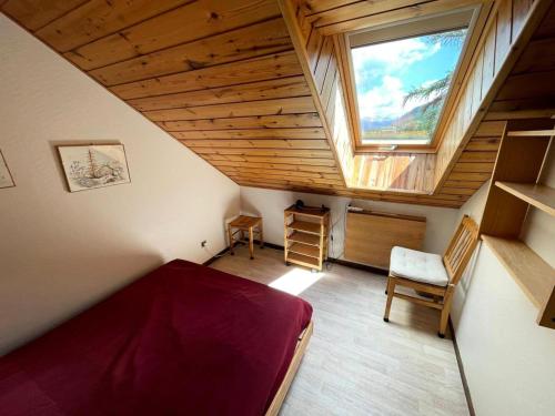 Cette chambre mansardée comprend un lit et une fenêtre. dans l'établissement Résidence Gardiole 4 - Appartement chaleureux · Centre village · Cheminée MAE-1614, au Monêtier-les-Bains
