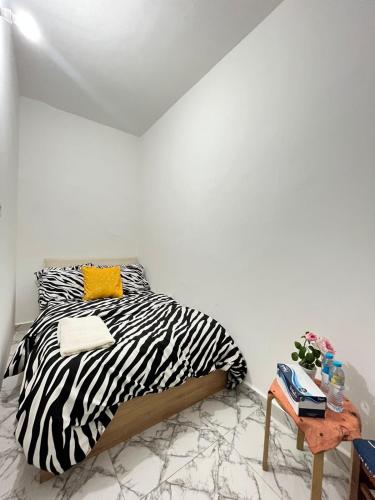 a zebra print bed in a white room with a table at Cozy STAY in Abu Dhabi