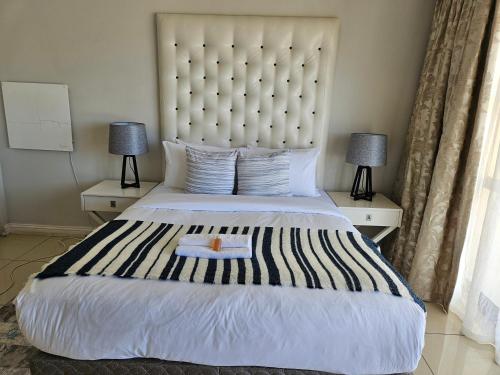 a bedroom with a large bed with two lamps at Mix Guesthouse in Gqeberha