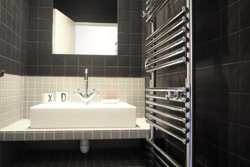 La salle de bains est pourvue d'un lavabo blanc et de carrelage noir. dans l'établissement Résidence Grande Masse - DUPLEX 4 pièces Rénové 8 personnes MAE-0094, aux Menuires