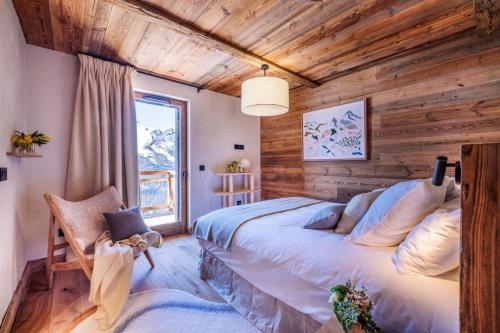 une chambre avec un lit et un mur en bois dans l'établissement Résidence Caseblanche - Chalet de luxe ALPEA· Accès direct aux pistes · Sauna · Ménage intermédiaire MAE-0234, à Saint-Martin-de-Belleville