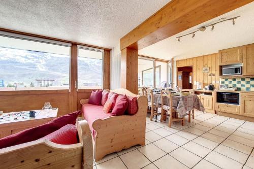 un salon avec un canapé et une cuisine avec une table dans l'établissement Résidence Aravis - Appartement spacieux · Skis aux pieds · Balcon vue station MAE-0244, aux Menuires