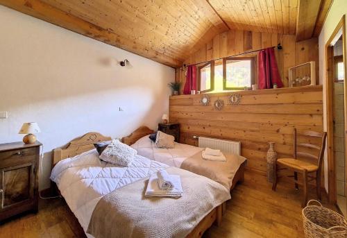 zwei Betten in einem Zimmer mit Holzwänden in der Unterkunft Résidence Les Granges - Chalet spacieux · Centre village des Granges · Sauna MAE-0184 in Saint-Marcel
