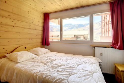 - une chambre avec un lit et une fenêtre donnant sur les montagnes dans l'établissement Résidence Les Lauzes - Appartement rénové · Départ et retour ski aux pieds MAE-0454, aux Menuires