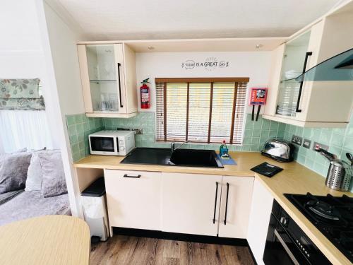 a small kitchen with a sink and a microwave at 3 Bedroom Lodge SG2, Lower Hyde, Isle of Wight in Shanklin