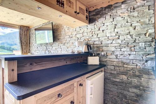 une cuisine avec un comptoir et un mur en briques dans l'établissement Résidence Caron - Appartement duplex rénové · Départ ski aux pieds · Balcon MAE-0694, aux Menuires