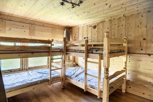 Ce lit se trouve dans un dortoir doté de 2 lits superposés et de murs en bois. dans l'établissement Résidence Caron - Appartement duplex rénové · Départ ski aux pieds · Balcon MAE-0694, aux Menuires