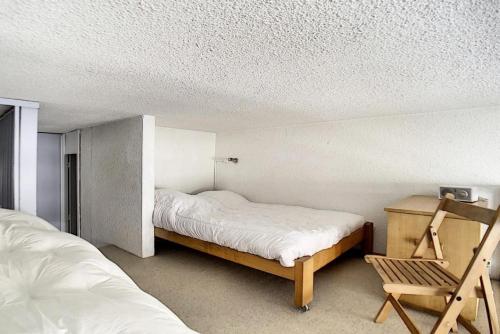 une chambre avec deux lits et une chaise dedans dans l'établissement Résidence Danchet - Appartement duplex moderne · Ski aux pieds · Balcon MAE-0714, aux Menuires