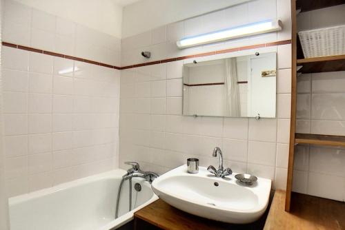 La salle de bains blanche est pourvue d'un lavabo et d'une baignoire. dans l'établissement Résidence Danchet - Appartement duplex moderne · Ski aux pieds · Balcon MAE-0714, aux Menuires