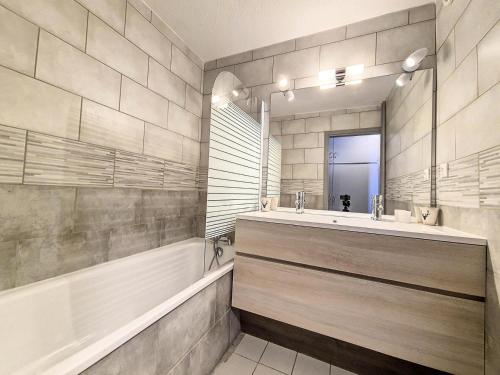 une salle de bain avec une baignoire, un lavabo et un miroir dans l'établissement Résidence Dorons - Appartement rénové · Centre station · Balcon MAE-0734, aux Menuires