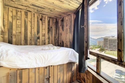 Ce lit se trouve dans une chambre en bois dotée d'une fenêtre. dans l'établissement Résidence Caron - Bel appartement entièrement rénové en 2016 MAE-0784, aux Menuires