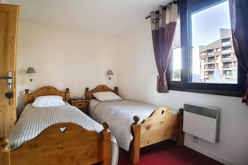 zwei Einzelbetten in einem Schlafzimmer mit Fenster in der Unterkunft Résidence Origanes - Appartement confortable · Départ et retour skis aux pieds · Balcon Parking inclus MAE-1034 in Les Menuires