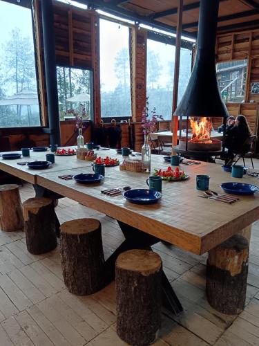 a large wooden table in a room with logs around it at Lobo Glamp corral de piedra in Amanalco de Becerra