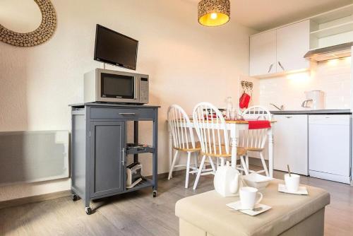 Il comprend une cuisine équipée d'un four micro-ondes et d'une table avec des chaises. dans l'établissement Résidence Boedette A - Appartement rénové · Départ et retour skis aux pieds · Balcon vue montagnes MAE-1114, aux Menuires