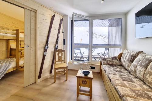 - un salon avec un canapé et des skis sur le mur dans l'établissement Résidence Soldanelles B - Appartement entièrement rénové · Au pieds des pistes · Parking inclus MAE-1174, aux Menuires