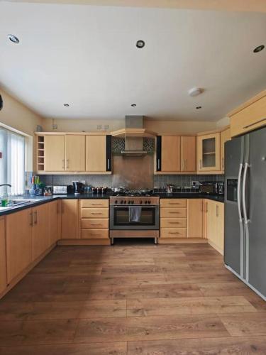 a large kitchen with wooden cabinets and stainless steel appliances at Stunning 5-bed House near NEC & BHX in Solihull
