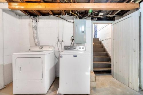 una lavatrice e asciugatrice in una stanza con scala di The Hideaway on Hazel- Luxury Smart Home w Hot Tub ad Ames
