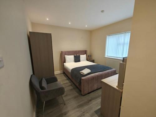 een slaapkamer met een bed, een stoel en een raam bij Luxury 5-bed House near NEC & BHX in Solihull