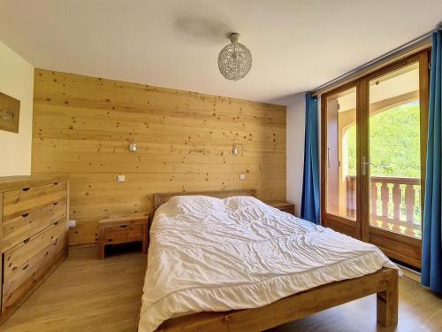 une chambre avec un lit et un mur en bois dans l'établissement Résidence Charmettes - Appartement en duplex spacieux · Au pied des pistes · Balcon MAE-1354, à Saint-Martin-de-Belleville