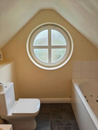 a bathroom with a window and a toilet and a tub at Luxury 5-bed House near NEC & BHX in Solihull