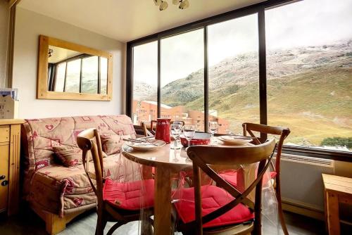 une table et des chaises dans une pièce avec une grande fenêtre dans l'établissement Résidence Biellaz - Appartement rénové, lumineux et chaleureux · Départ et retour skis aux pieds · Vue montagne MAE-1474, aux Menuires