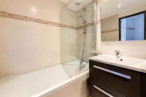 La salle de bains est pourvue d'une baignoire blanche, d'un lavabo et d'une baignoire. dans l'établissement Résidence Median - Appartement rénové · Proche des pistes · Balcon MAE-1534, aux Menuires