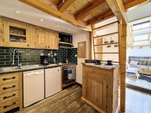 une cuisine avec des armoires en bois, un évier et une cuisinière dans l'établissement Résidence Biolley - Appartement moderne mansardé · Au pied des pistes · Centre village MAE-1664, à Saint-Martin-de-Belleville