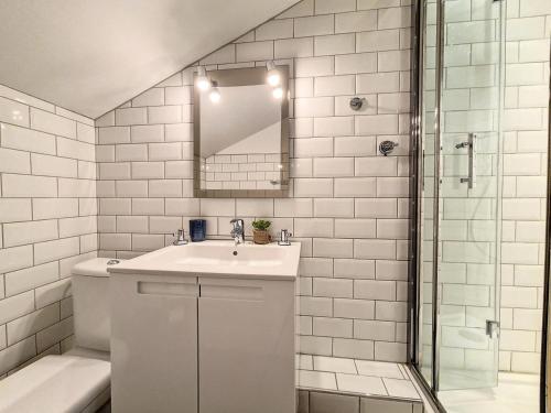 a white bathroom with a sink and a mirror at Résidence Biolley - Appartement moderne mansardé · Au pied des pistes · Centre village MAE-1664 in Saint-Martin-de-Belleville