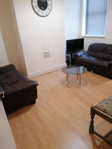 a living room with a couch and a table and a clock at Hygis Home Of Relaxations in Stoke on Trent