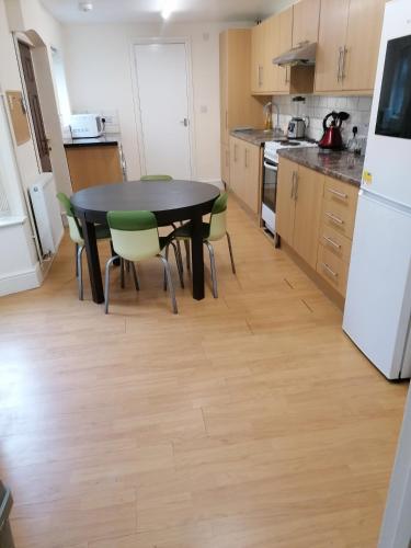a kitchen with a black table and green chairs at Hygis Home Of Relaxations in Stoke on Trent