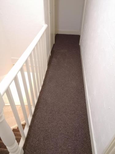 a hallway with a white staircase with carpet at Hygis Home Of Relaxations in Stoke on Trent