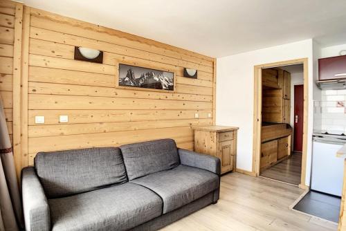 - un salon avec un canapé et un mur en bois dans l'établissement Résidence Dorons - Studio rénové · Centre station · Balcon MAE-1904, aux Menuires