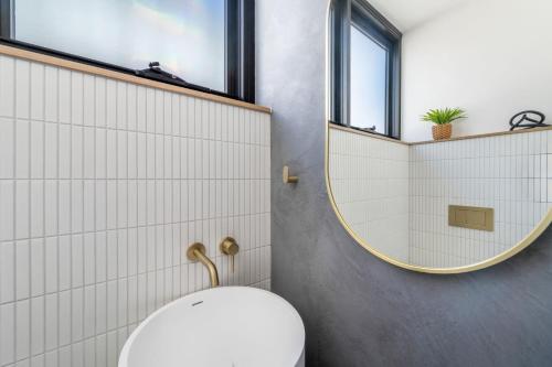 a bathroom with a toilet and a round mirror at Luxurious brand new 3 bedroom house near the ocean in Mooloolaba