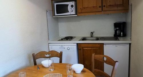 une petite cuisine avec une table et un micro-ondes dans l'établissement Résidence Median - Appartement confortable · Proche des pistes · Balcon MAE-2334, aux Menuires