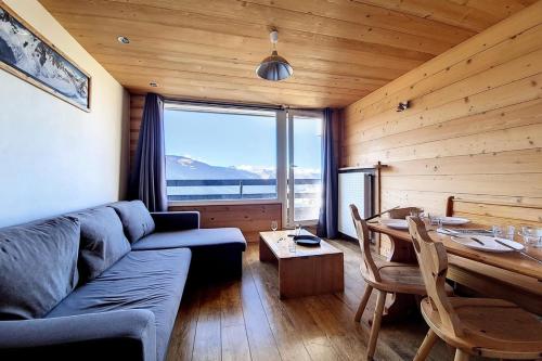 un salon avec un canapé et une table avec vue dans l'établissement Résidence Lac Du Lou - Appartement confortable · Au pied des pistes · Balcon MAE-2484, aux Menuires