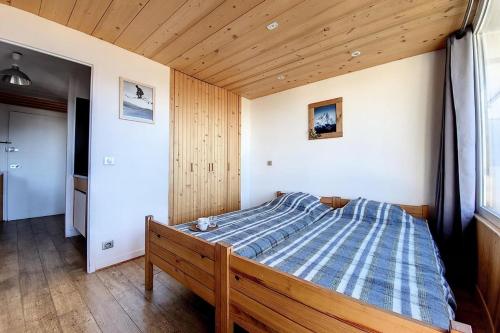 un lit dans une chambre avec un plafond en bois dans l'établissement Résidence Lac Du Lou - Appartement confortable · Au pied des pistes · Balcon MAE-2484, aux Menuires