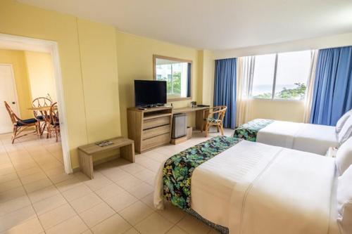 a hotel room with two beds and a television at GHL Relax Hotel Costa Azul in Santa Marta