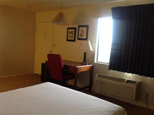a hotel room with a bed and a desk and a window at Eunice Plaza Motel in El Monte