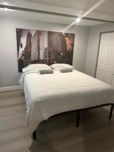 a bedroom with a large bed with a painting on the wall at Cozy Apartments Woodside near Manhattan in Queens